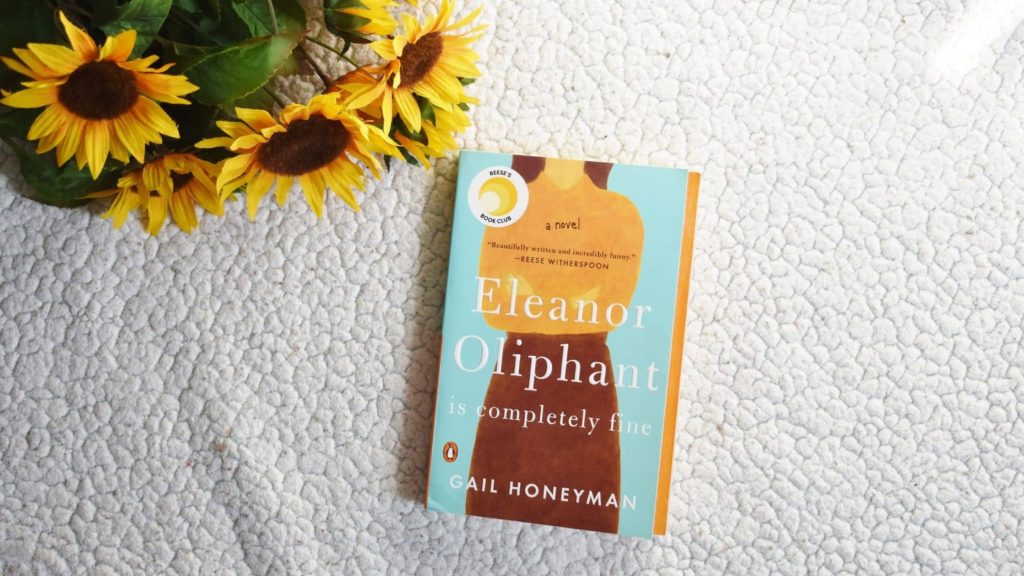 White background with sunflowers in the top left corner and the book Eleanor Oliphant is Comletely Fine in the middle