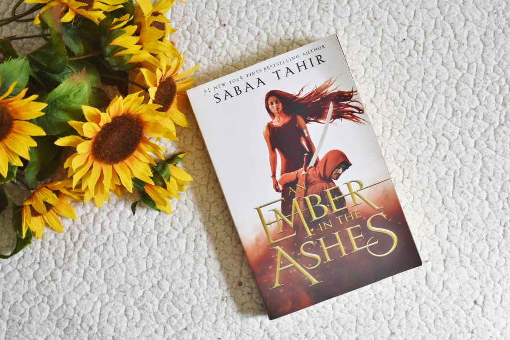 An Ember in the Ashes book and sunflowers
